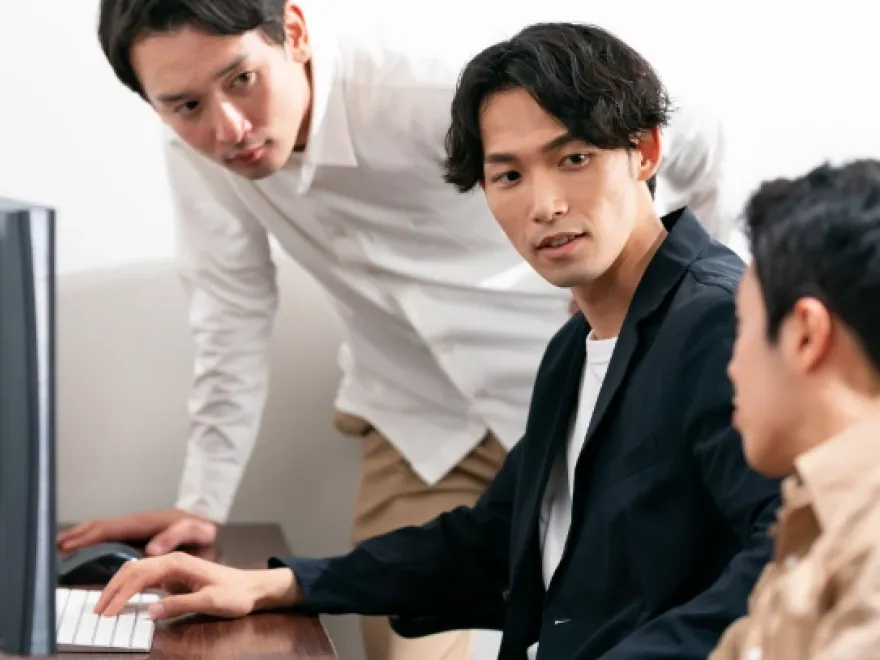 パソコンの画面を見ながら打ち合わせをする社員たち